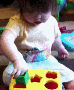 Kid playing w/ shape sorter toy gives up and takes off lid to put in shape