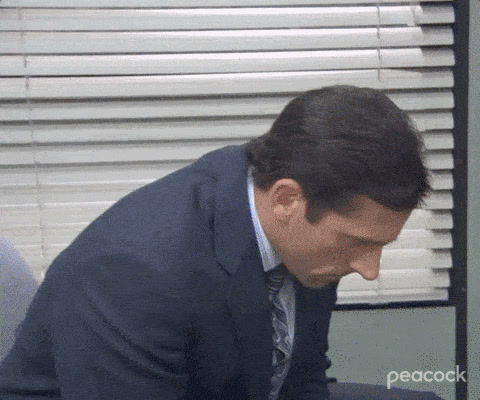 The Office: Michael Scott, hunched over in a suit, slowly looks up with a stunned, wide-eyed stare.