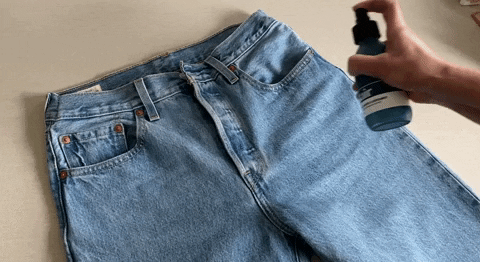 Gif of a pair of blue jeans being sprayed with Kair's Wild Juniper & Bergamot Signature Finishing Spray