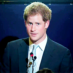 Prince Harry shaking his head in front of microphones.