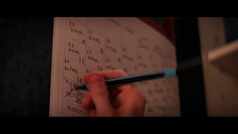 Hand writing a reminder onto a paper wall calendar