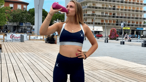 Mulher com roupa de academia enquanto bebe água