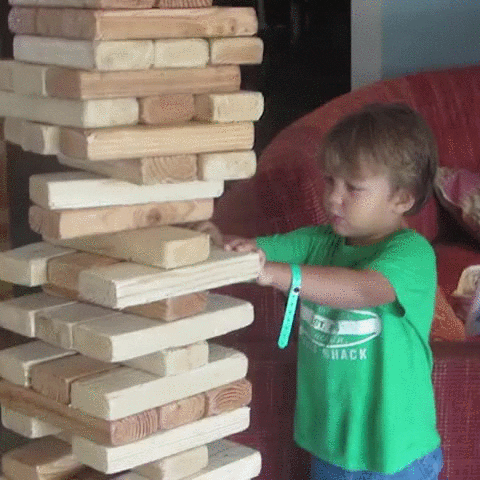 Un niño pequeño jugando al Jenga que ve frustrado su intento de sacar una pieza y acaba con la torre en su cara