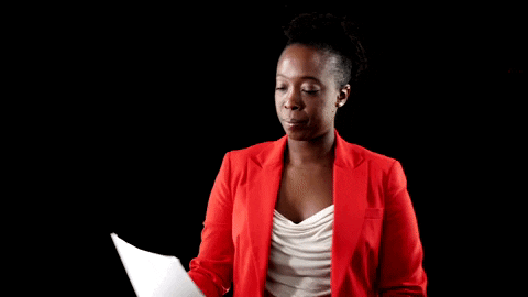 Woman in a red blazer reading a paper document closely before signing