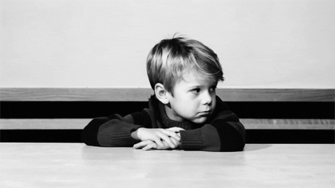 A little kid leaning on a table and thinking