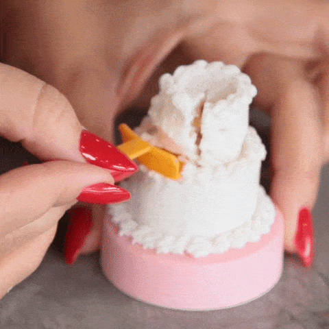 A GIF of a miniature 2 tiered cake showing a slice being served