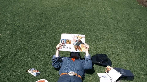 Chris Farren in sunglasses reading a magazine