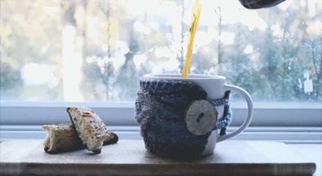 Someone pouring herbal tea into a mug with a knitted coozy.