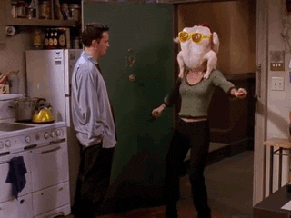 Gif from the show Friends with Chandler and Monica. Monica's dancing with her head inside of a chicken. The chicken has yellow sunglasses
