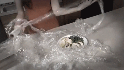 Femme qui se bat dans sa cuisine avec des mètres de cellophane