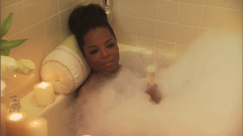 Oprah taking a bubble bath with a glass of wine