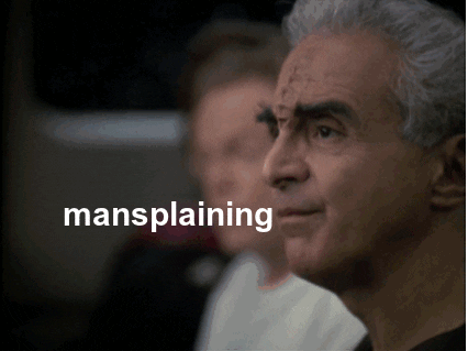 A white man in the foreground speaks, with the text "mansplaining" next to his mouth. A white woman leans in from the background giving a look of disbelief of what the man just said.