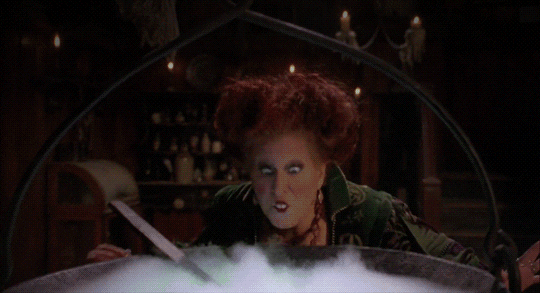 A GIF of Winifred from the movie 'Hocus Pocus'. She's making magic over the cauldron.