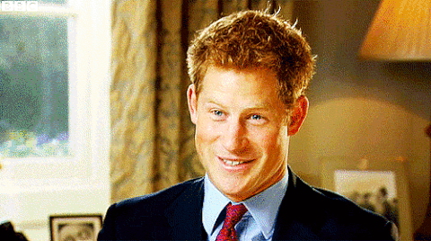 Prince Harry smiling and laughing while sitting in an office. 