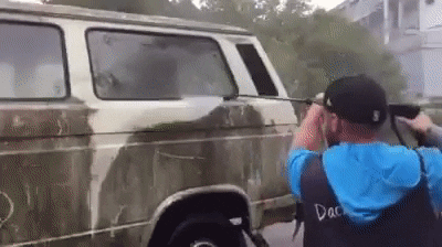 Man using pressure washer to clean a white car