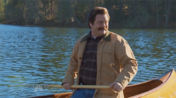 Parks and Rec character canoeing in a yellow boat in a lake