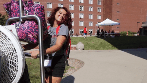 Student moving into dorm with a cart full of belongings.