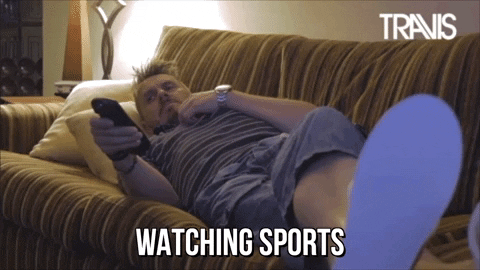 A man watching TV while lying on a couch