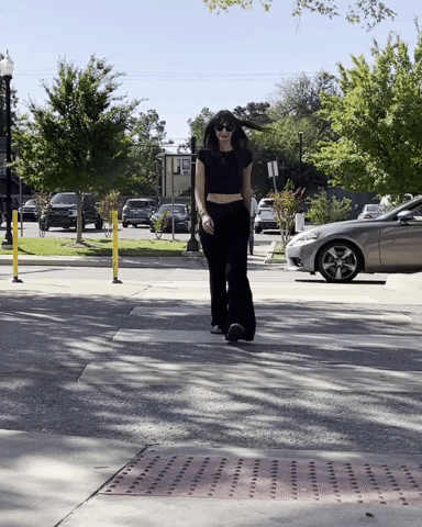 Woman walking briskly across a sunlit crosswalk in a small town