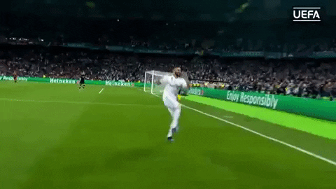 Jogador de futebol com uniforme branco comemorando o gol em um estádio fora do Brasil