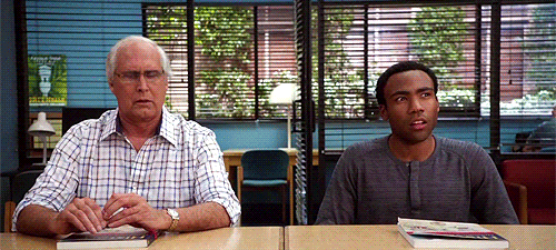 Characters from TV's Community sit around a table with confused expressions