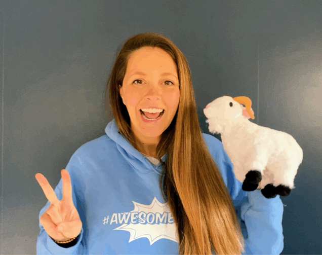 Admin Evangelist LeeAnne Rimel holding up a peace sign in one hand and a small Cloudy plush animal in the other and doing a shoulder shimmy dance