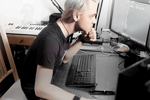 Um homem está sentado na frente do PC coçando o queixo enquanto a frase "I am a programming god!" aparece.