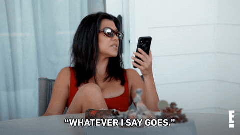 The gif of Kourtney Cardashian sitting on the chair in a red swimsuit, holding her phone and saying "Whatever I say goes".