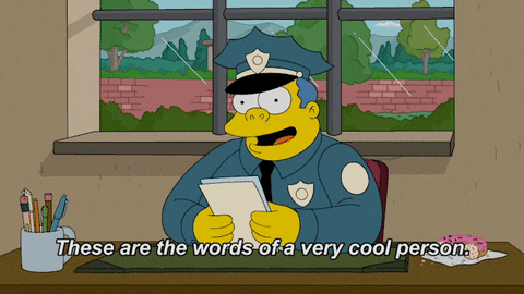 Personagem dos Simpsons, policial, fardado, sentado à mesa, lê um documento e diz que as palavras ali escritas referem-se a uma pessoa muito legal.