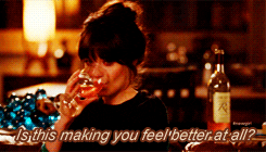 Jess from tv show "New Girl" crying while drinking a glass of wine.