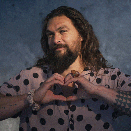 Gif of Jason Momoa smiling and making a heart shape with his hands