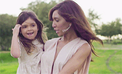 Farrah and her daughter walk across a green lawn. Farrah and her daughter walk across a green lawn.