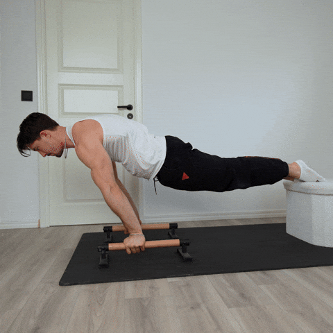 Elevated planche lean demonstration on parallettes with the feet raised on a box
