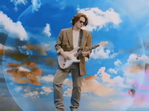 A man plays electric guitar surrounded by multicolor clouds.