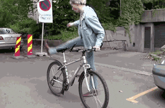 Animated GIF of person throwing a leg over top of bike and swinging both legs, push off of street to propel bike