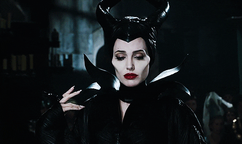 Gif clip of Angelina Jolie as Maleficent in full evil queen regalia, smiling with slow, malicious delight