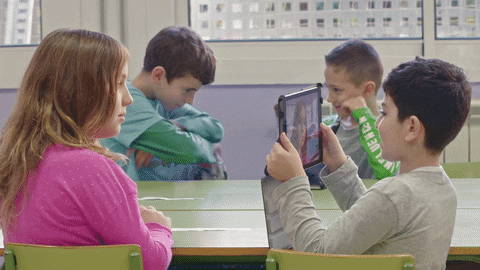Quatro crianças em uma escola com modelo de educação 4.0, realizando um projeto em dulpa com um tablet.