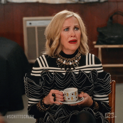 GIF of Moira from Schitt's Creek holding a cup of tea and asking, "What is it?!"