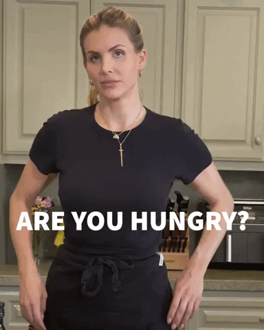 Woman in a kitchen with her hands on her hips asking if you are hungry