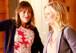 Ann Perkins and Leslie Knope from Parks and Rec dance excitedly together. 