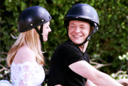 Sabrina and Harvey on a motorcycle smiling.
