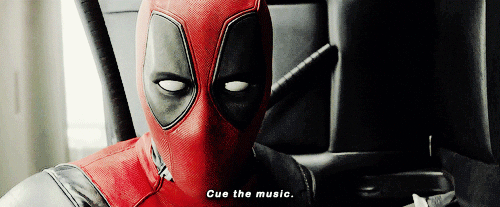 GIF of Deadpool (Ryan Reynolds) looking right at the camera, holding up his guns and saying "Cue the music."