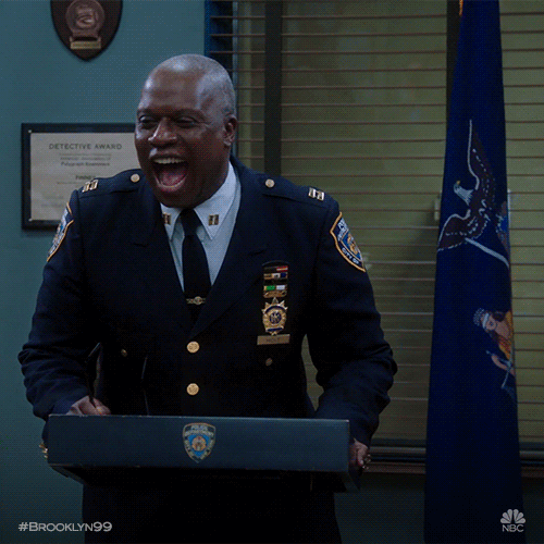 Police captain Raymond Holt from TV show Brooklyn 99 laughing in front of a lectern