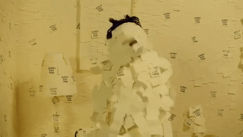 person covered in post it notes dancing in a room that is also covered in post it notes.