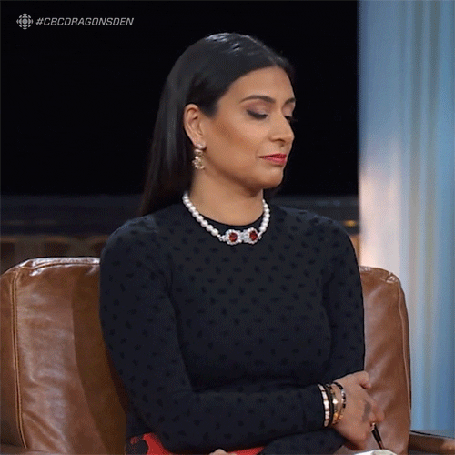 A woman wearing a black shirt with arm crossed sitting on a brown leather chair looking astonished