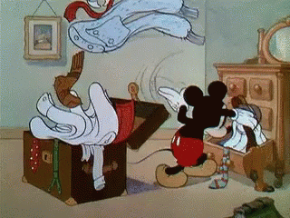 Micky Mouse throwing lots of clothes into suitcase