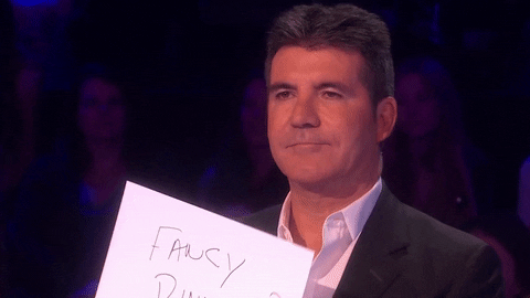 Simon cowell holding up a sign that says 'fancy dinner?'