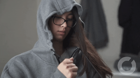 Girl in a hoodie pulling the drawstring so the hood covers her face
