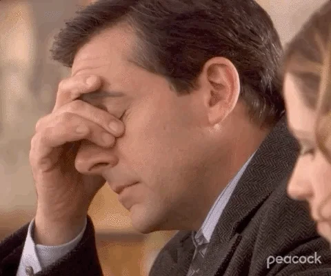 A man in a suit facepalms in frustration (The Office)