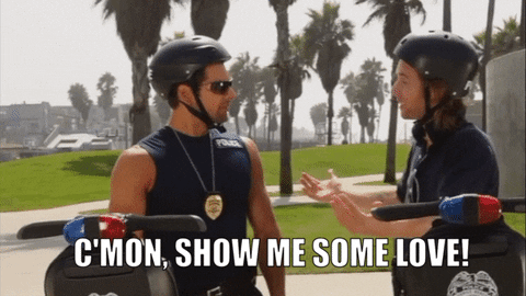 Animated GIF: One US police officer goes to hug his reluctant colleague while the caption reads "C'mon, show me some love!"